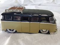 Side view of black and beige Volkswagen bus model with roof rack