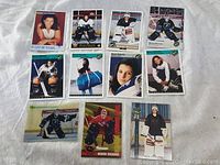 Photo showing 11 Manon Rheaume hockey cards in various poses and team uniforms on white textile background.