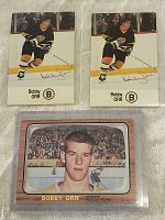 Three Bobby Orr cards: two identical showing him skating in Boston Bruins colors with signature, and one portrait card.