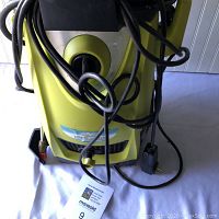 Front view of green Sun Joe electric pressure washer showing power cord, hose, and front label with specifications.