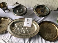 Photo showing a collection of silver plated serving dishes and decorative items on a white cloth background.