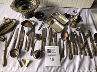 Wide view of all silver plated silverware and serving pieces arranged on white surface, showing knives, forks, trays, bowls, and specialty utensils.