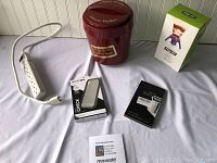 Overall view of the lot items including the vintage Johnnie Walker red ice bucket, power strip, phone case, bottle opener, and collectible figure in box.