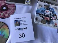 Close-up of several PS3 game discs including Madden NFL 25 and a stack of accessories.