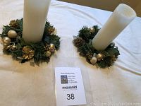 Full view of two Christmas wreath candle holders on white tablecloth with candles included