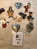 Photo showing full assortment of ornaments including heart-shaped tins, Santa, snowman, deer, female figurine and houses.