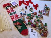 Photo showing assortment of tapered candles, red bows, Christmas stocking, Santa figurine, and small wrapped gift box ornaments.