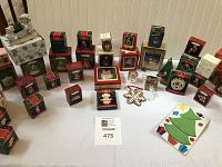 Overview of many Hallmark Keepsake Christmas ornaments in original boxes and a ceramic snowman figurine on a wrapped box.