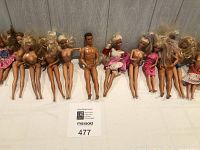 Full view of 15 dolls laid out in a row showing various states of dress and hairstyles.