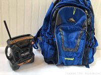 Ridgid X4 portable battery radio next to blue High Sierra backpack showing size and condition.