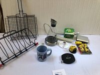 Photo showing turkey roaster rack, grilling rack, glass teapot, bags, light fixtures, power strip, Stanley tape measure and laser level, yellow hose connectors, metal case, mug