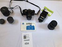 Overview of Minolta X-700 camera with accessories spread around including lenses, carrying case, flash, manual, and film.