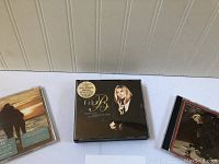 Two CD cases side by side, focus on Barbra Streisand concert CD in foreground, another CD with sunset couple image partially visible