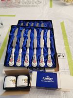 Two boxes of bone china handled cutters arranged in blue satin-lined cases, showing 11 cutters total.