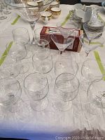 Photo showing the 4 martini glasses, oversized martini-shaped candy dish, and 12 wine glasses arranged on a table with other dishware in background