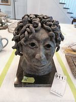 Front view of the clay sculpture bust showing face with curly hair and mounted on black marble base with auction tag visible.