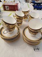 Fourteen stacked Wedgwood tea cups arranged alongside sixteen stacked saucers showing the floral and gold detailed pattern.