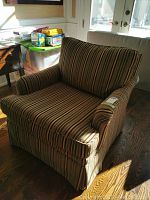 Front and side views of a large arm chair with brown striped upholstery and padded arms and backrest.