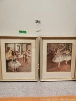 Two framed ballet dancer prints side by side leaning against wall, showing full view of frames and artwork.