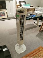 Front view showing fan's vertical vent slats, oscillation dial on top, and round base.