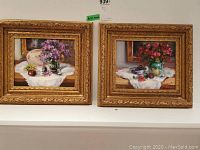 Two paintings side by side in matching ornate gold frames on a shelf