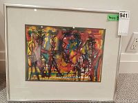Framed abstract watercolor painting with vibrant multicolor depiction of stylized figures, silver metal frame, white mat overlay, visible signature.
