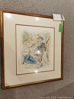 Photo showing first framed watercolour artwork with group of figures, matted and framed, includes visible mat border and wall carpet background.