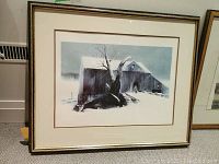 Framed winter farm print depicting a barn and tree covered in snow, viewed at an angle showing condition and frame details.