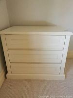 Front view of white bedside table with 3 drawers showing panel details on drawer fronts