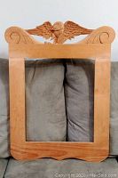 Full view of rectangular wooden frame showing eagle carving at top.