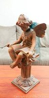 Front view of resin statue showing girl with butterfly wings reading a book on pedestal