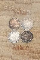 Four Canadian silver five cent coins dated 1907, 1912, 1918, and 1919 arranged on a textured surface, showing the reverse sides with floral wreath designs and denomination.