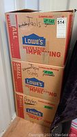 Three stacked Lowe's boxes labeled for kitchen tools, glass, leopard tape, cords, garden supplies