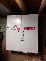 Front view of cabinet doors showing United Delco/AC and SERVICE logos, keyed lock and key hanging.