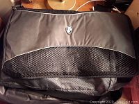 Close-up of a grey and black packing cube with mesh ventilation panel, zip closure, and Heys shield logo on fabric