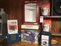 Photo showing boxed Micro Furnace solid state heater, Hunter heater with blue base, MVP 5 in 1 air compressor/inflator unit, Assamese Sam 5 security alarm box, two Handy Bulb lights in packaging, Pro Reel camera