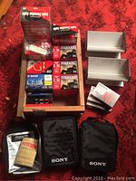 Wooden tray containing various sealed cassette tapes, two metal holders, two Sony zippered cases