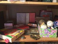 Shelf view showing wooden pattern block set in box, decorative tin box and small brass ashtray among other items