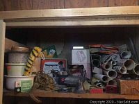Shelf with vintage flowerpots, fuzzy yellow/black striped object, rope, Mattel Greenie Stik-M-Caps box, camera equipment and miscellaneous vintage items.