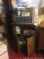 Microwave cart with doors open containing various kitchen items including cookware and boxes.