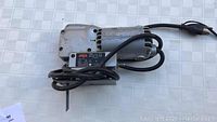 Metal-bodied Skil Model 514 Deluxe Jig Saw with power cord coiled around the body, showing its general condition and design.