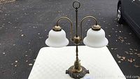 Full view of double globe table lamp with frosted glass globes and decorative brass base.