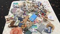 Top view showing a variety of crafting supplies and decorative items spread on a surface including wooden figures, fabric, and colorful embellishments