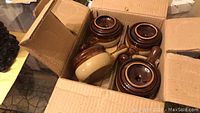 Four new onion soup crocks with lids in an open cardboard box.