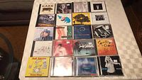 Twenty music CDs arranged on a table surface, showing front covers clearly.