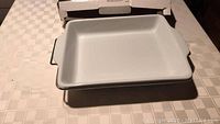 White ceramic baking dish placed inside the metal serving stand, showing the size and shape of the baking dish with short handles.