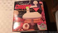Photo of Smart Chopper food chopper box showing branding and product image, highlighting included whipping paddle and chopping blade.