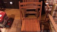 Single wooden folding chair showing slatted seat and backrest detail.