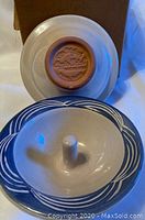 Photo showing the base of the Apple Baker baking dish with the maker's mark and the underside of the dish with central post and decorative blue rim pattern.