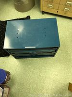 Top view of blue metal shop cabinet showing flat top surface with light scratches and holes